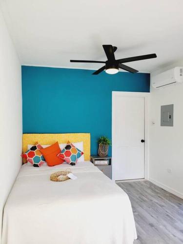um quarto com uma cama branca e uma parede azul em Studio Soliá-Slice Of Paradise em Bridgetown