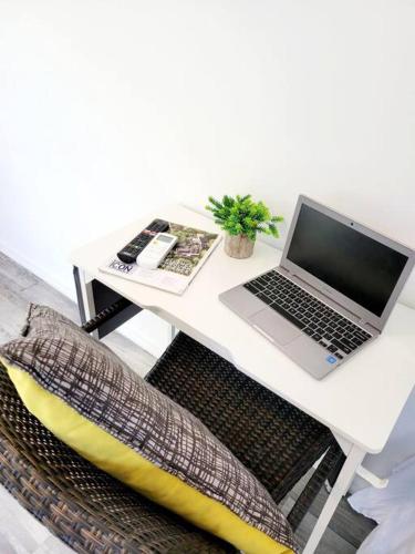 um computador portátil sentado numa secretária branca com uma cadeira em Studio Soliá-Slice Of Paradise em Bridgetown