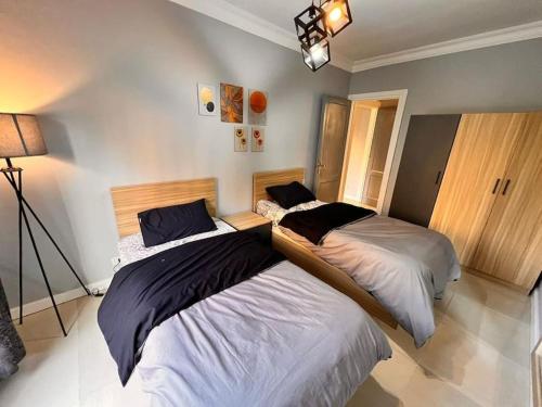 2 Betten befinden sich in einem Zimmer mit einer Lampe. in der Unterkunft stylish with garden 3bdrm 2 bath in Madinaty