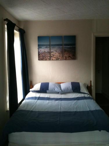 a bed in a bedroom with two paintings on the wall at Grosvenor Guest House in Hastings