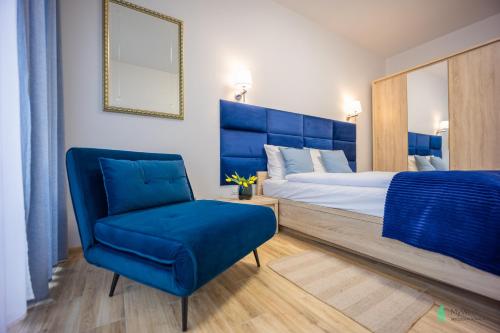 um quarto com uma cama azul e uma cadeira azul em Apartament Gambit, Ogrody Pieniawskie, MyWeek em Polanica-Zdrój