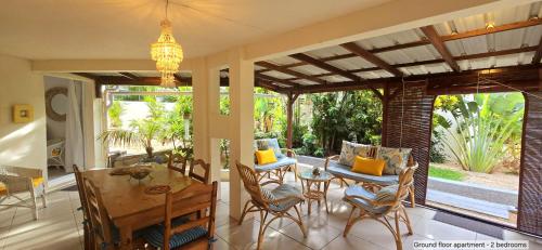 une salle à manger avec une table et des chaises sur une terrasse dans l'établissement Lakaz Del Sol - NEWLY RENOVATED modern and elegant apartments with luxurious garden, pool, barbecue and bar area, à Tamarin