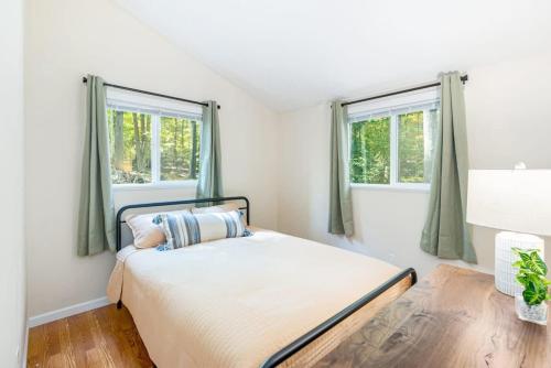 a bedroom with a bed and two windows at Cabin w Hot Tub, Huge Deck, Firepit & WiFi! in Hedgesville