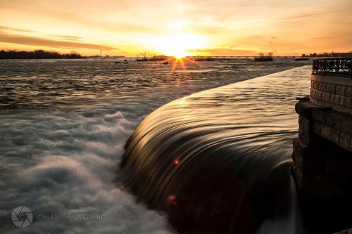 una puesta de sol sobre un cuerpo de agua con olas en Niagara Stone Bliss en Cataratas del Niágara