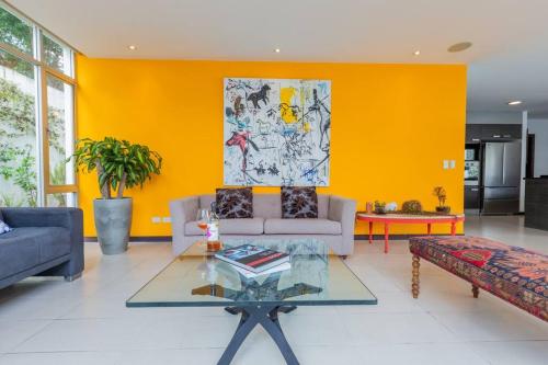 a living room with a couch and a yellow wall at Villa Azul Apartment in Quito