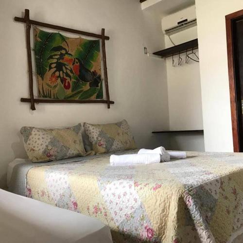 a bed in a room with a picture on the wall at Pousada Porto Jandaias in Porto Seguro