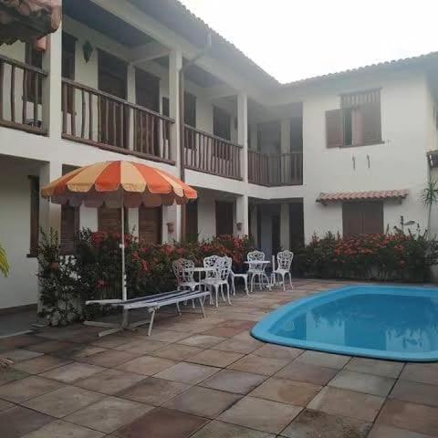 a patio with chairs and an umbrella next to a building at Pousada Porto Jandaias in Porto Seguro