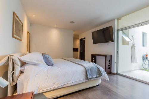 a bedroom with a large bed and a television at Villa Azul Apartment in Quito