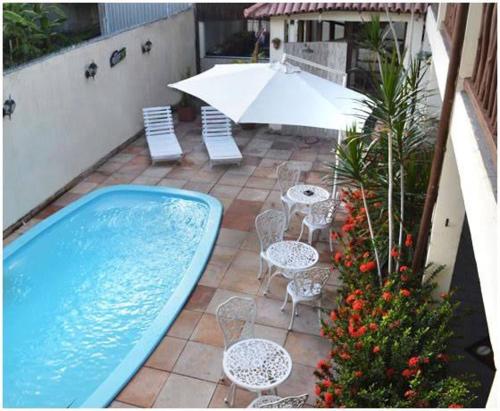a patio with a pool and chairs and an umbrella at Pousada Porto Jandaias in Porto Seguro