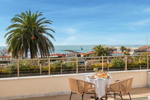 a table on a balcony with a view of the ocean at Hotel Excelsior in Marina di Massa
