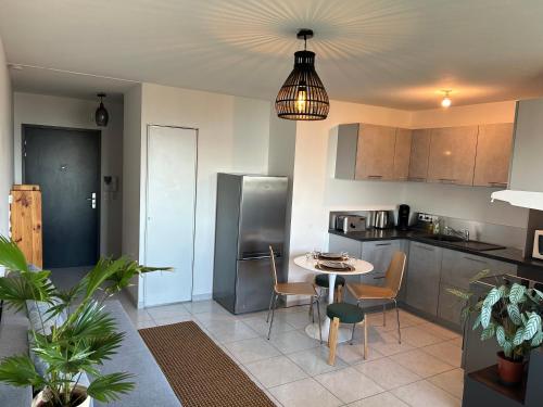 une cuisine avec une table, des chaises et un réfrigérateur dans l'établissement Jolie vue au calme, à Évian-les-Bains