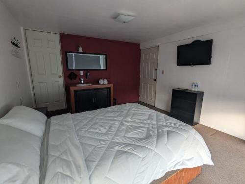 a bedroom with a large white bed and a flat screen tv at Hotel María Bonita in Tlaxcala de Xicohténcatl