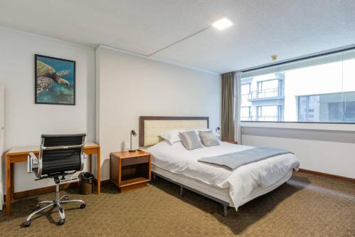 a bedroom with a bed and a desk and a chair at Akros Galapagos Suite in Quito