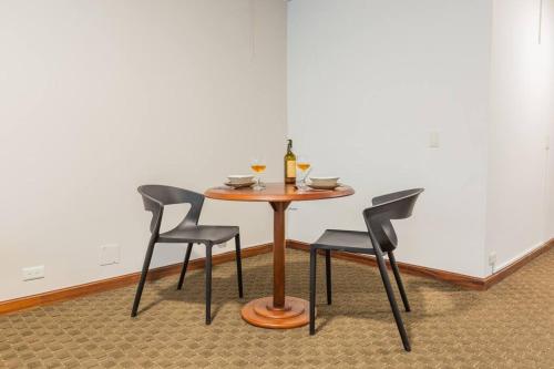 a table with three chairs and a bottle of wine at Akros Galapagos Suite in Quito