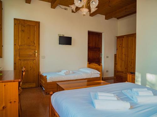 1 dormitorio con 2 camas y TV en la pared en B&B Villa Erika, en Villa San Martino