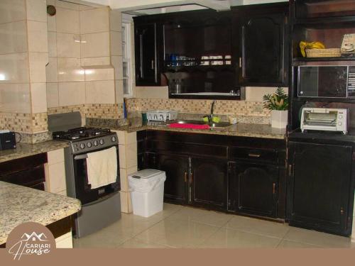 cocina con armarios negros y fogones en Full house, 11BR, 12BA, 10 min from SJO Airport, en Heredia