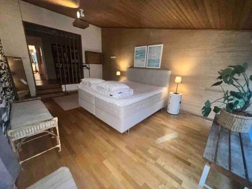 a bedroom with a large white bed and wooden floors at Cozy house near the sea in Höllviken