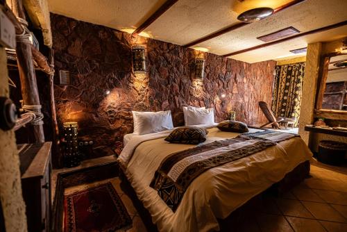 a bedroom with a large bed in a room with stone walls at Hotel Xaluca Dades in Boumalne