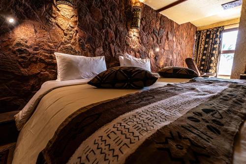 a bedroom with a large bed with stone walls at Hotel Xaluca Dades in Boumalne