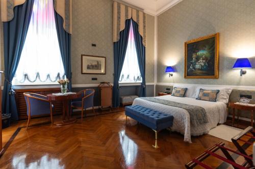 a bedroom with a king sized bed and a table at Grand Hotel Ortigia in Siracusa