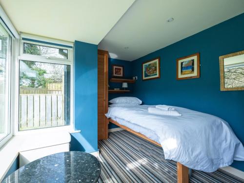 a blue bedroom with a bed and a glass table at Beachside in Polzeath