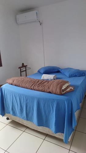 a bed with a blue blanket on top of it at Quarto c/ Ar Split 01 cama casal , banheiro social compartilhado ( fora do quarto ) in Tabapira