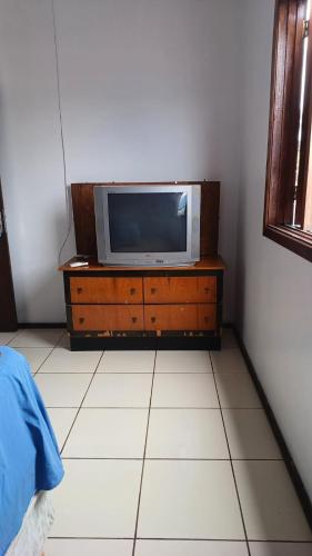 - une télévision assise sur une commode dans une pièce dans l'établissement Quarto c/ Ar Split 01 cama casal , banheiro social compartilhado ( fora do quarto ), à Tabapira