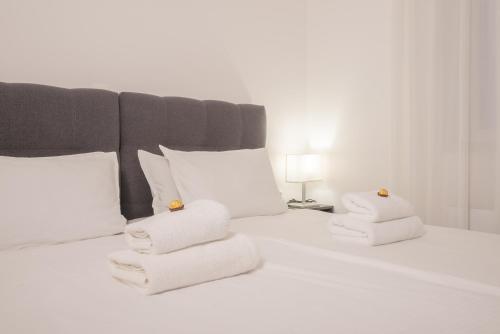 Una cama blanca con dos toallas plegables. en Goldberg Apartments Osijek en Osijek