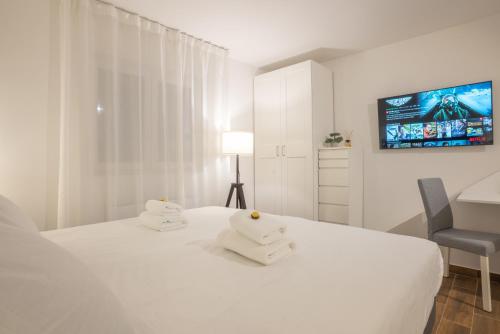 a white bedroom with a white bed and a chair at Goldberg Apartments Osijek in Osijek