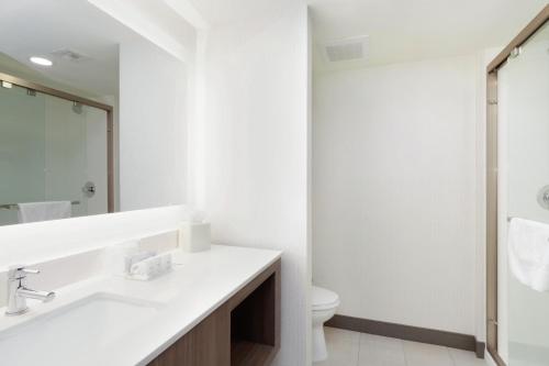 a white bathroom with a sink and a toilet at Holiday Inn Phoenix Airport, an IHG Hotel in Phoenix