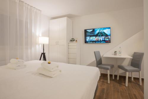 a white bedroom with a bed and a table and chairs at Goldberg Apartments Osijek in Osijek