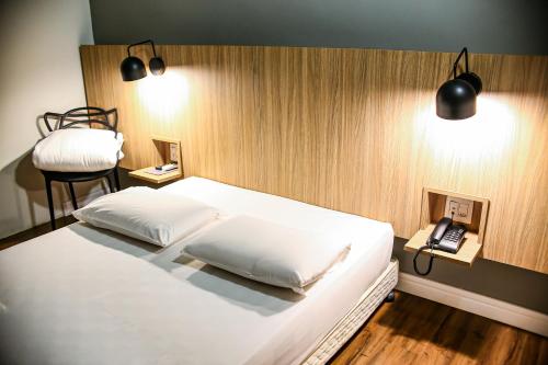 a bedroom with a white bed and a telephone at Graal Inn Uberaba in Uberaba