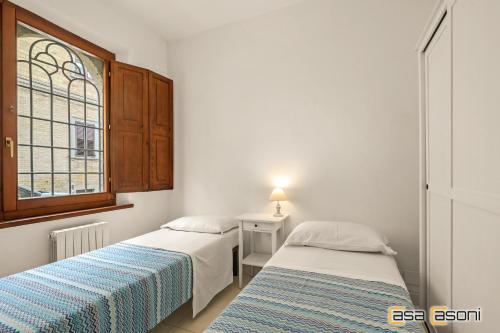 two beds in a small room with a window at I Cappuccini - Casa Vacanze in Osimo