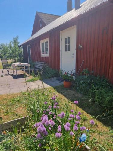 a red house with a garden with flowers in front of it at Bo på lantgård in Motala