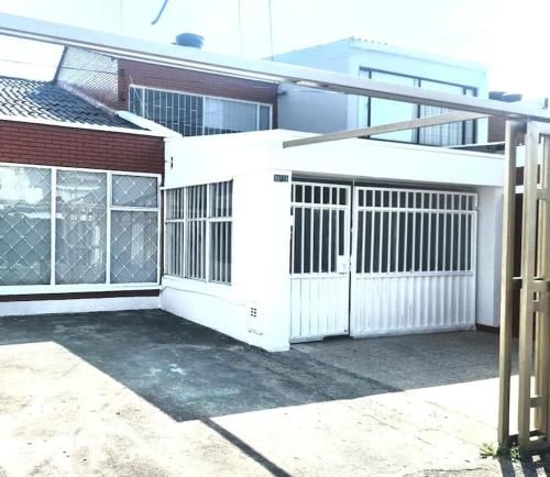 a white garage with a gate and a building at Casa Cerca del Aeropuerto: Spa con Sauna y Jacuzzi in Bogotá