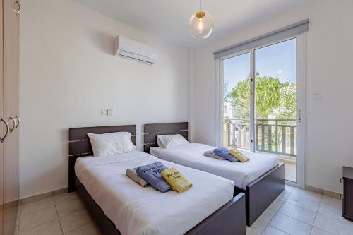 two beds in a room with a large window at Villa Lynn Chill Out Seaview in Ayia Napa