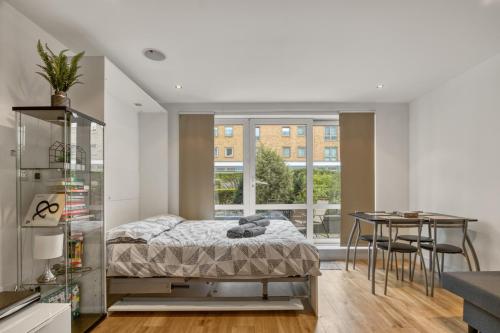 倫敦的住宿－Modern Chíc Studio Chelsea，一间卧室配有一张床铺和一张桌子,还设有一间厨房