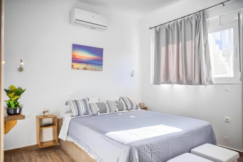 a white bedroom with a bed and a window at La mer stegna in Archangelos