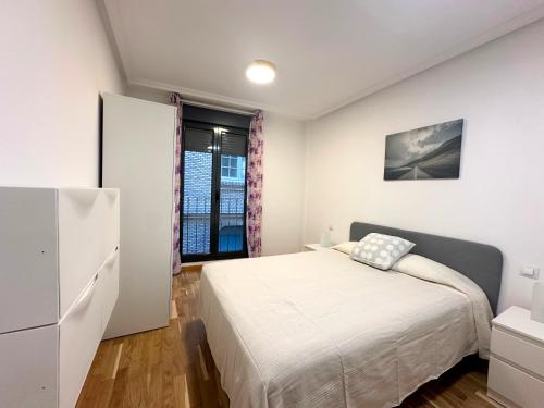 Habitación blanca con cama y ventana en Dos Torres César Augusto - Larga temporada, en Zaragoza