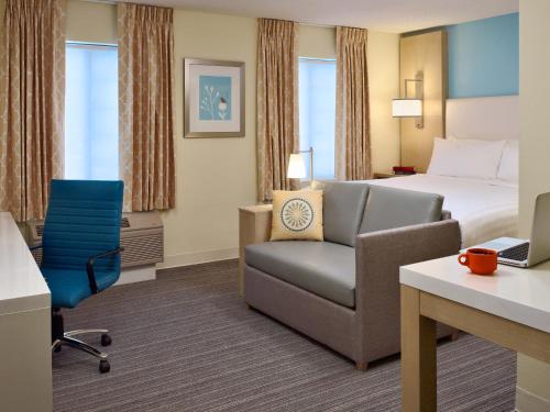 a hotel room with a bed and a chair and a desk at Parsippany Suites Hotel in Parsippany