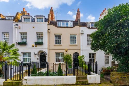 a large white house with a black fence at Stunning Knightsbridge Townhouse With Patio in London