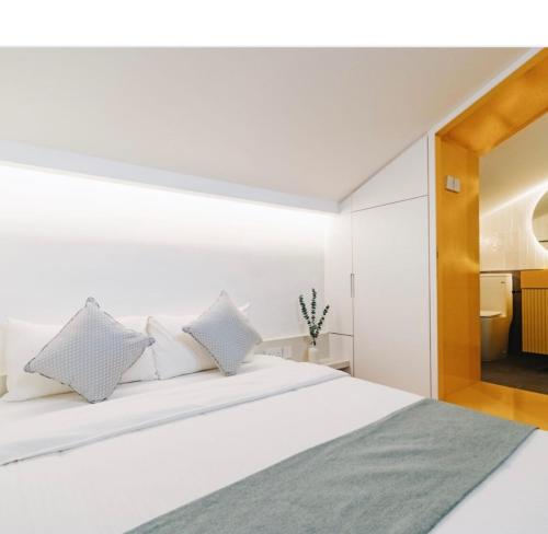 a bedroom with a white bed with white pillows at Social-Inn Norris Road Apt in Singapore