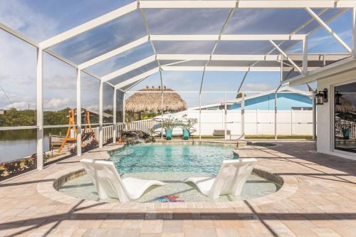 a swimming pool with two white chairs and a building at The Pearl - Pool W Screen On Canal - Boat Rental in Cocoa Beach