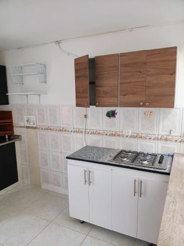 a kitchen with white cabinets and a stove top at Casa portón negro in Bogotá
