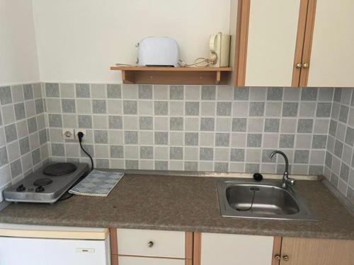 a kitchen counter with a sink and a stove at Trident Studios and Apartments in Kavos