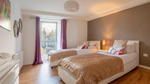 a bedroom with two beds and a window at AC19 Lower North Aisle - Luxury Self Catering 2 Bedroom Apartment in Fort Augustus