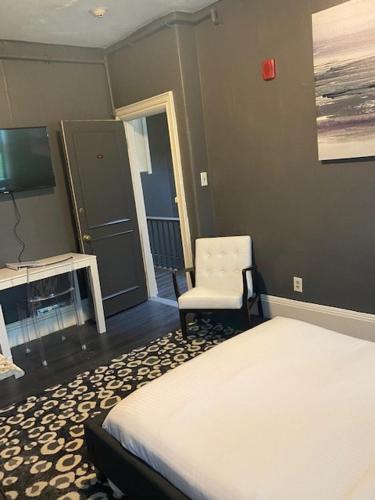 a bedroom with a bed and a chair and a television at Premier Suites Bay Village in Boston
