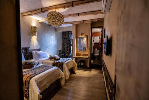 a hotel room with two beds and a mirror at Hotel Xaluca Dades in Boumalne