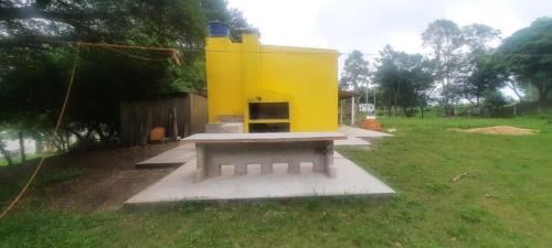 un bâtiment jaune avec banc dans un champ dans l'établissement Casa da Vigia, à Santana do Livramento