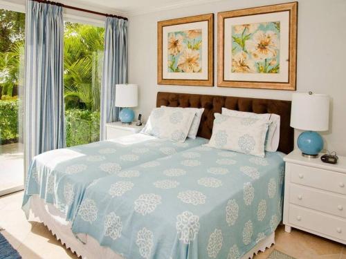 a bedroom with a blue and white bed with a window at 117 Sapphire Beach Condo in Christ Church